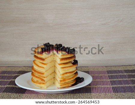 Fluffy pancakes with currant syrup on wooden background