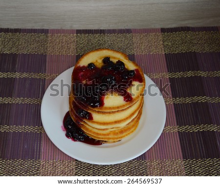 Fluffy pancakes with currant syrup on wooden background