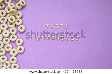 Words Tasty Breakfast Written With Pasta Letters on violet background with cereal rings