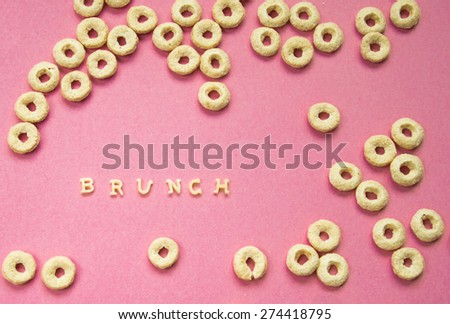 Word Brunch Written With Pasta Letters on pink background with cereal rings