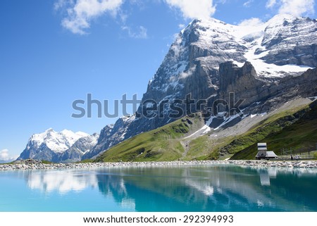 The north face of the Eiger, with the Wetterhorn in the background, reflected in the reservoir, also showing the museum of the Eiger North Face.