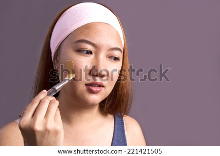 Spa face mask.teen girl applying facial clay mask. Beauty treatments.