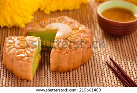Traditional green beans paste moon cakes on white plate with teacup. Chinese mid autumn festival foods.