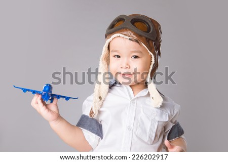 Happy kid playing with toy airplane. Cheerful boy smiling