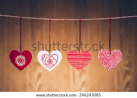 Red textured hearts hanging on rope. Vintage style. Isolated on wooden background. Valentines heart concept.