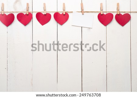Blank instant photo and small red paper heart hanging on the clothesline. On white wooden background. Love heart hanging on wooden texture background, valentines day card concept