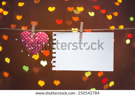 heart and needles with note on clothesline. Valentines day concept. Over heart bokeh background