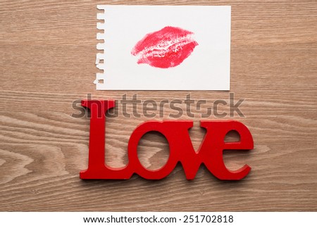 LOVE wooden letter. Lipstick kiss on paper note. Valentine\'s Day concept on wooden background