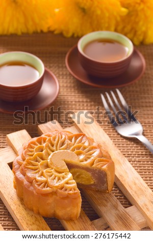 Retro vintage style Chinese mid autumn festival foods. The Chinese words on the mooncakes means assorted fruits nuts, not a logo or trademark. Traditional mooncakes on table setting with teacup.