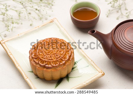 Chinese mid autumn festival foods. Traditional mooncakes on table setting with teacup.