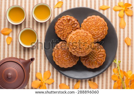 Mooncake and tea,food and drink for Chinese mid autumn festival. Traditional mooncakes on table setting with teapot.