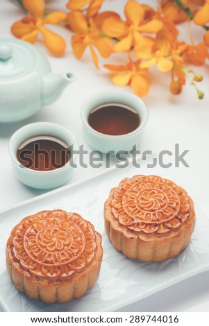 Retro vintage style Chinese mid autumn festival foods. Traditional mooncakes on table setting with teacup.