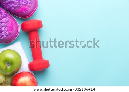Sneakers and dumbbells fitness on a gray background. Different tools for sport. Sport shoes and water with set for sports activities on tiled floor.