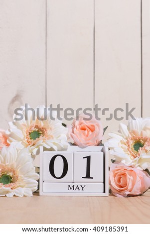 May 1st. Happy May Day white block wood calendar decorated with spring flowers on wood table.