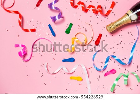Flat lay of Celebration. Champagne bottle with colorful party streamers on pink background.