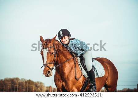 young beautiful woman rides a horse wearing a helmet. Horseback Riding.