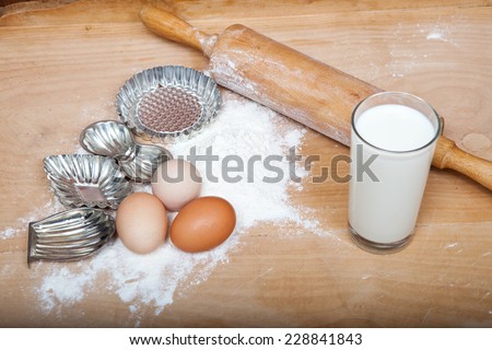 retro silver biscuit cutters, wooden rolling pin, and dough ingredients on old wooden table