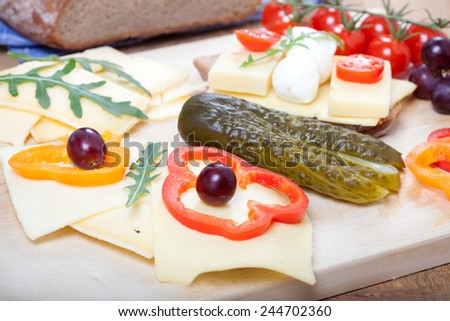 traditional german snack with cheese bread, sweet pepper, cherry tomatoes, pickled cucumber, mozzarella, on rustic wooden board,