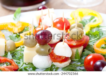 Cheese Skewers on plate with fresh green rocket, with mozzarella, cherry tomatoes, olives, sweet pepper,