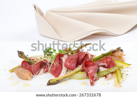delicious menu starter with a plate of green marinated asparagus, smoked duck breast and sweet banana chutney, napkin in background