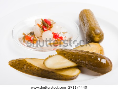 sliced marinated pickles on plate with spice and onion, white background,