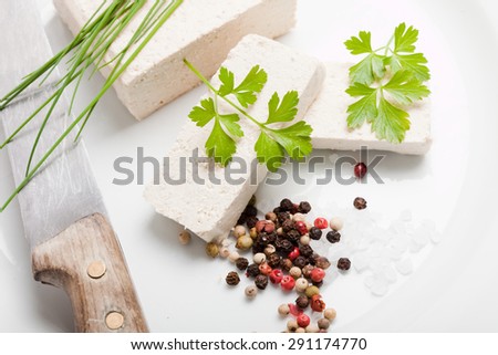 tofu slices with parsley, salt, pepper and chives on white plate, with old knife