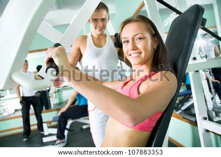 Fitness. Woman at the gym doing arms exercises on a machine