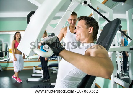 Fitness. Yung man at the gym doing arms exercises on a machine