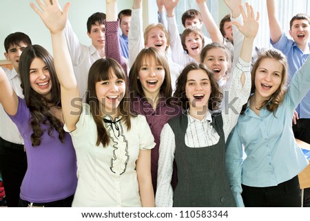 Group of happy students with hands raised