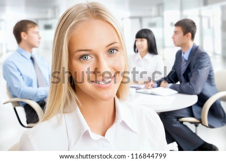 Closeup portrait of attractive business woman smiling with colleagues working in background