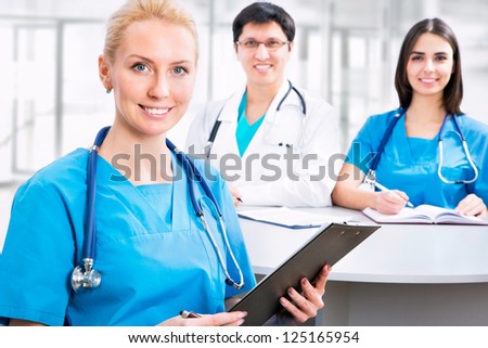 Portrait of a smart female doctor sitting in front of his team and smiling