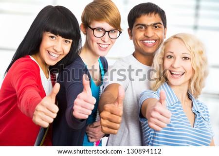 Group of happy students giving the thumbs-up sign