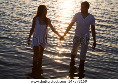 Loving couple walking by the sea at sunset