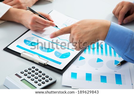 Image of man's hand pointing at business document during discussion at meeting