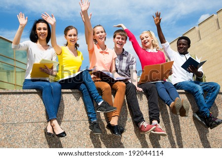 Excited students with arms outstretched outdoors