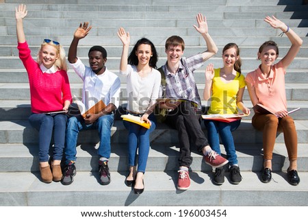 Excited students with arms outstretched outdoors