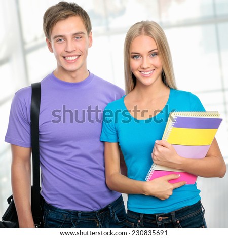 Group of happy young teenager students standing and smiling with books and bags