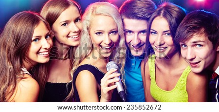 Young people singing into microphone at party