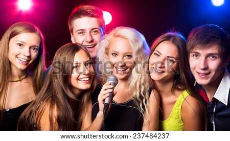 Young people singing into microphone at party
