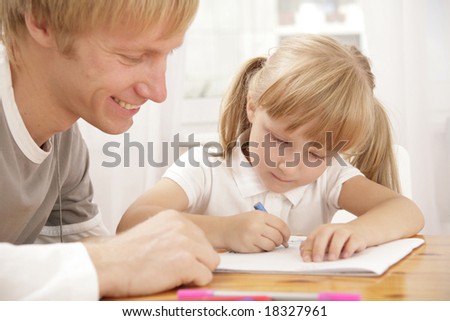 Portrait of little girl painting something and her father looking at this