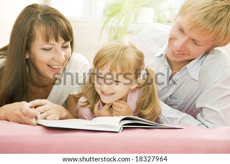 Portrait of happy family reading the book together at home