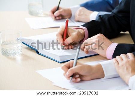 Hands taking notes, focus is on the pen
