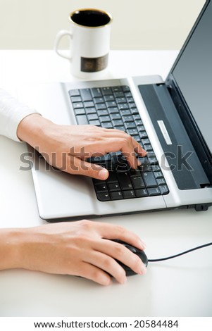 Feminine hands typing on laptop keyboard and touching mouse