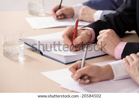 Three business people making notes. Close-up