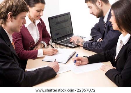 Four business people making notes and typing