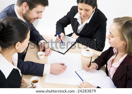 Four people gathered together around the table and discuss ideas at business meeting