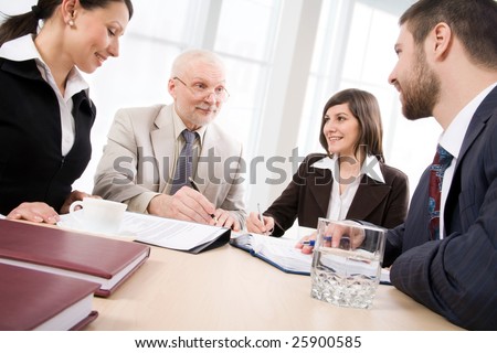 Four business people sit round a table and communicate