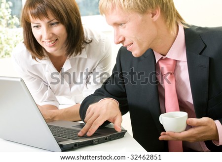 Image of successful businessman touching key of laptop with pretty female near by