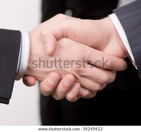 One man shakes another man by the hand. Close up