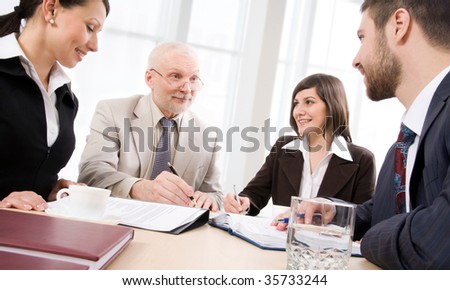 Four business people sit round a table and communicate
